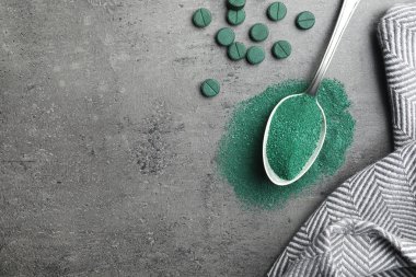 Spirulina tozu ve gri arka plan, metin için yer ile üstten görünüm haplarla kaşık