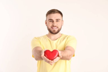 Beyaz arka plan üzerinde ahşap kalp tutan genç adam