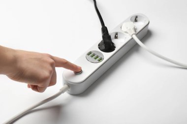 Kadın beyaz zemin üzerine, closeup uzatma kablosu, güç düğmesine basmak. Elektrik teknisyen ekipmanları