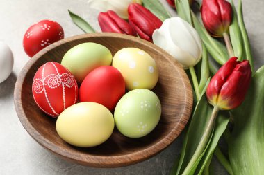 Bir kase boyalı Paskalya yumurtaları ve ışık arka plan bahar çiçekleri