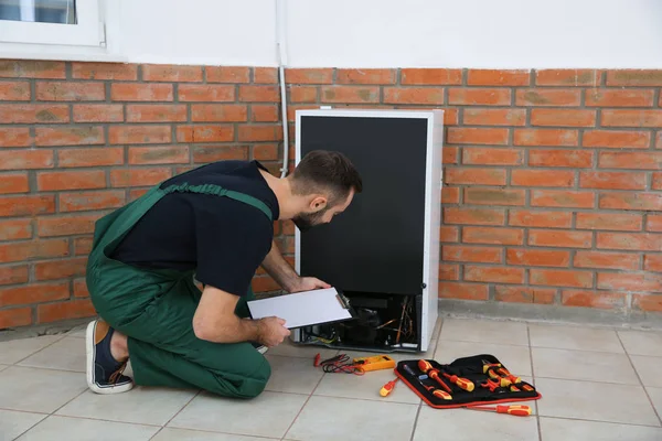 Manliga Tekniker Med Urklipp Undersöker Kylskåpet Inomhus — Stockfoto