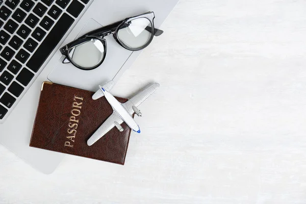 Flat lay composition with passport, laptop, toy plane and space for text on light background. Travel agency