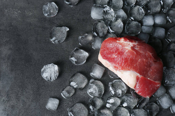 Flat lay composition with raw meat and ice cubes on dark background