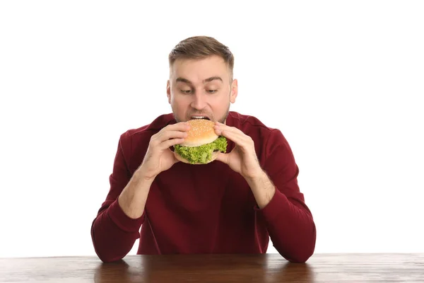 Jovem Comendo Hambúrguer Saboroso Mesa Fundo Branco — Fotografia de Stock