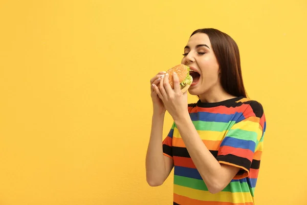 Młoda Kobieta Jedzenie Smaczne Burger Kolor Tła Miejsca Tekst — Zdjęcie stockowe