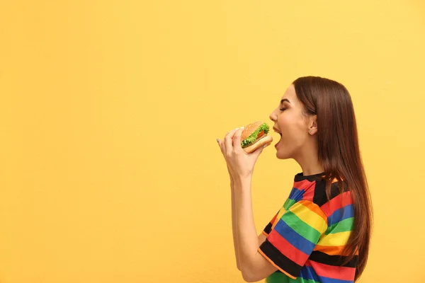 Młoda Kobieta Jedzenie Smaczne Burger Kolor Tła Miejsca Tekst — Zdjęcie stockowe
