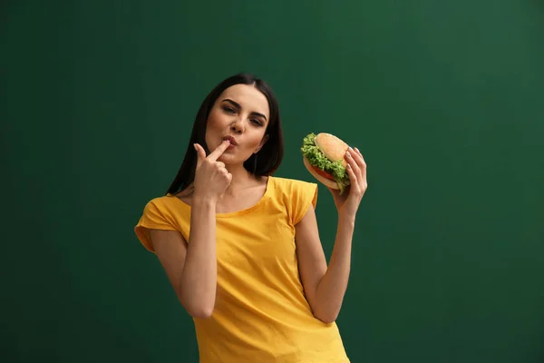 Jeune Femme Manger Hamburger Savoureux Sur Fond Couleur — Photo