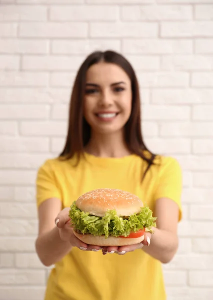 レンガの壁の近くのおいしいハンバーガーを持つ若い女性 — ストック写真
