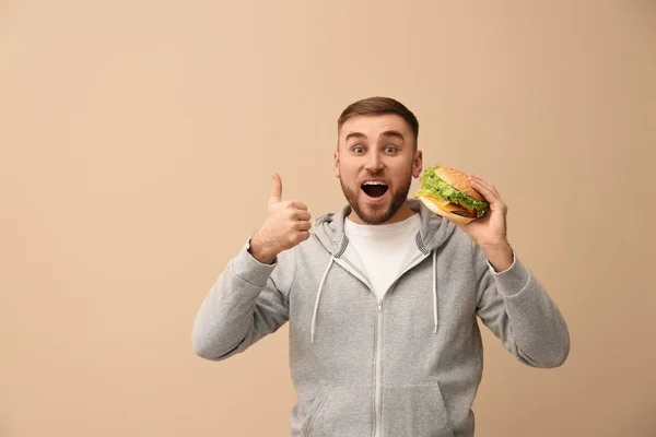 Young Man Eating Tasty Burger Color Background Space Text — Stock Photo, Image