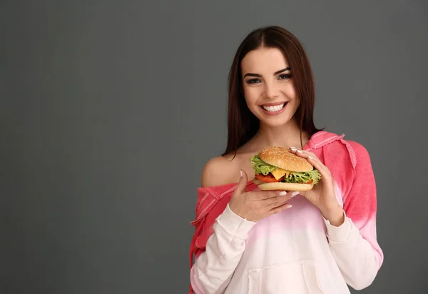 Jovem Com Hambúrguer Saboroso Fundo Cinza Espaço Para Texto — Fotografia de Stock