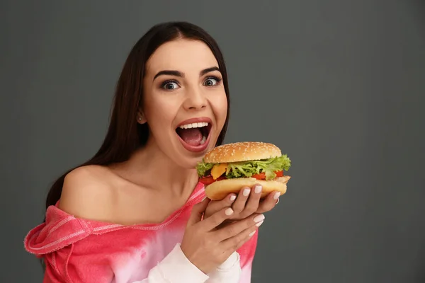 Jonge Vrouw Smakelijke Hamburger Eten Grijze Achtergrond Ruimte Voor Tekst — Stockfoto