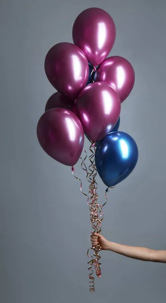 Woman holding bunch of balloons on grey background, closeup