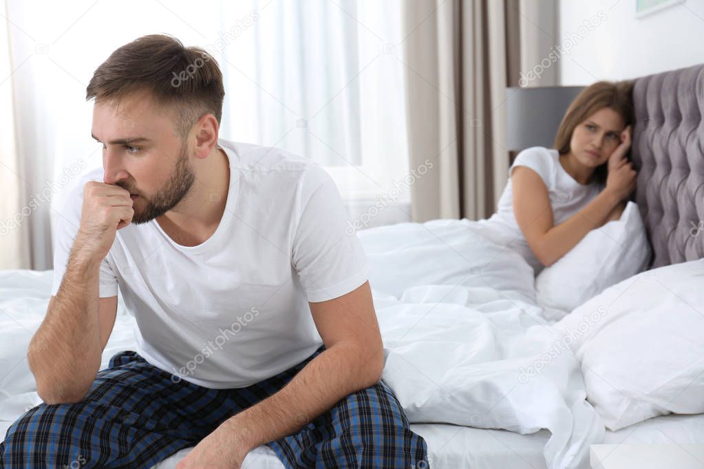 Young couple with relationship problems ignoring each other in bedroom