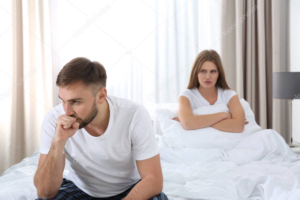 Young couple with relationship problems ignoring each other in bedroom