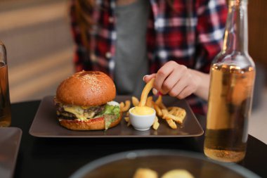 Patates kızartması ve lezzetli burger Cafe, closeup yeme genç kadın