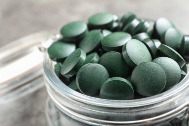 Gri tablo, closeup haplarla yeşil spirulina ile Cam Kavanoz