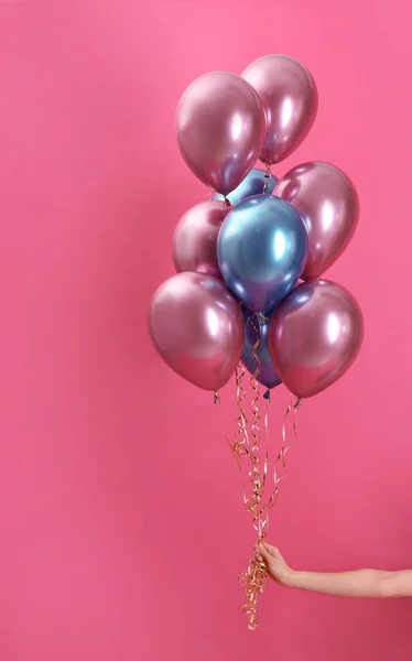 Woman holding bunch of balloons on color background, closeup