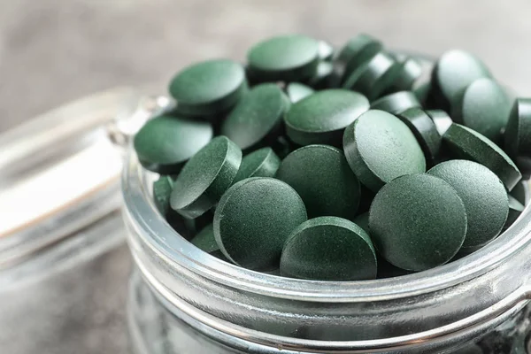 Glazen Pot Met Groene Spirulina Pillen Grijze Tafel Close — Stockfoto