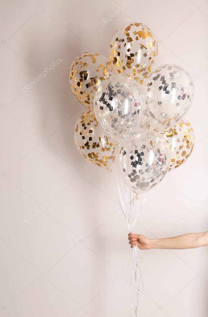 Woman holding bunch of balloons on white background, closeup