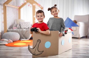 Dürbün ve yatak odasında karton tekne ile oynayan sevimli küçük çocuklar