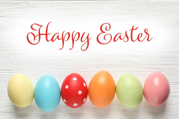 Színes festett tojások és szöveg Boldog húsvéti fa háttér lapos laikus összetétele — Stock Fotó