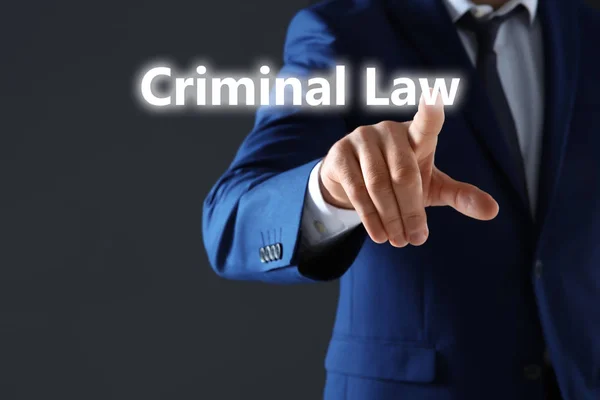 Бізнесмен, який вказує на текст CRIMINAL LAW на темному тлі — стокове фото