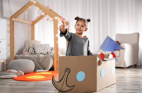 Nettes kleines Mädchen spielt mit Pappboot im Schlafzimmer — Stockfoto