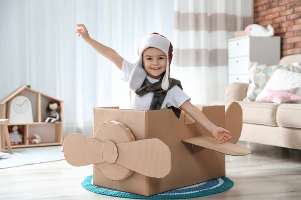 Netter kleiner Junge spielt mit Pappflugzeug im Wohnzimmer — Stockfoto