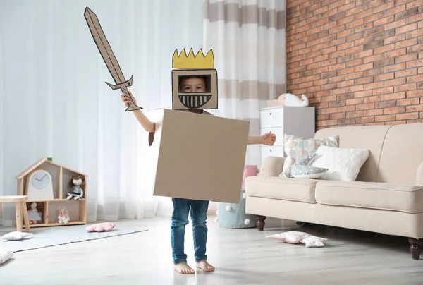 Lindo niño jugando armadura de cartón en la sala de estar —  Fotos de Stock