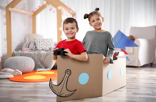 Niedliche kleine Kinder spielen mit Fernglas und Pappboot im Schlafzimmer — Stockfoto