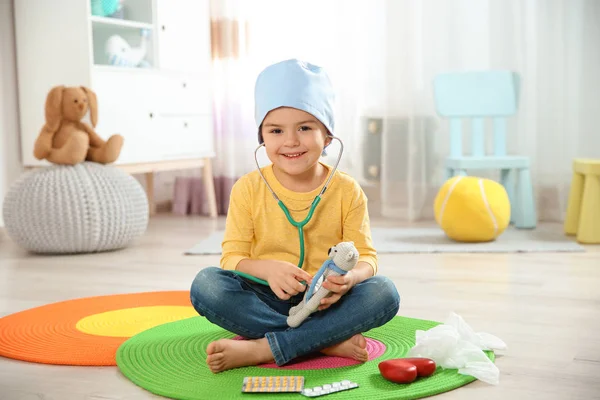 Enfant mignon s'imaginant médecin tout en jouant avec stéthoscope et ours jouet à la maison — Photo