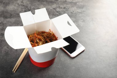 Smartphone ve Çin noodle gri masada. Food teslim