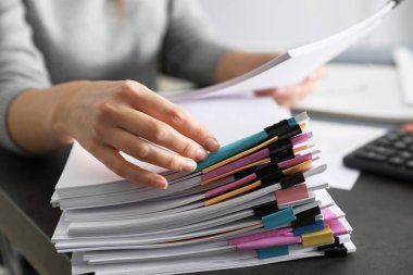 Ofis çalışanı masadaki belgelerle çalışıyor, yakın plan.