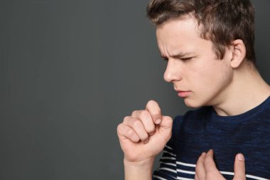 Öksürük koyu arka plan üzerinde acı genç çocuk. Metin için yer