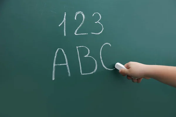 Kleines Kind, das Buchstaben und Zahlen auf Kreide schreibt, Nahaufnahme — Stockfoto