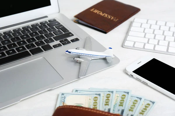 Smartphone con portátil, dinero y avión de juguete sobre fondo claro. Agencia de viajes — Foto de Stock