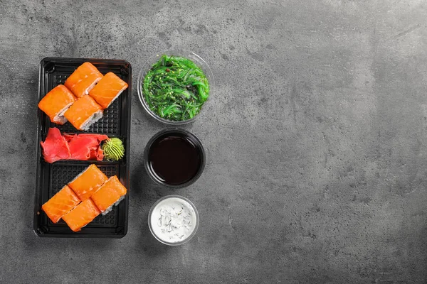 Composição de leigos planos com rolos de sushi e espaço para texto em mesa cinza. Entrega de alimentos — Fotografia de Stock