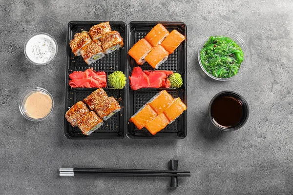 Flat lay composition with sushi rolls on grey table. Food delivery