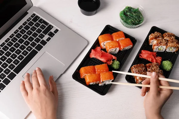 Γυναίκα τρώει νόστιμο σούσι κυλίνδρους στο χώρο εργασίας, κινηματογράφηση σε πρώτο πλάνο. Διανομή φαγητού — Φωτογραφία Αρχείου