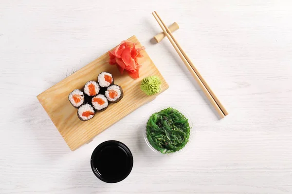 Flat lay composition with sushi rolls on white wooden table. Food delivery