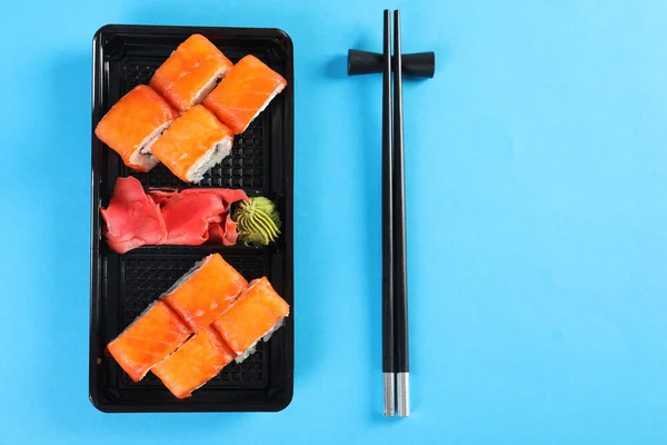 Flat lay composition with sushi rolls on color background, space for text. Food delivery