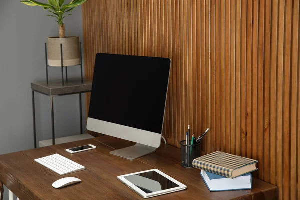 Elegante lugar de trabajo con computadora moderna cerca de la pared de madera. Espacio para texto —  Fotos de Stock