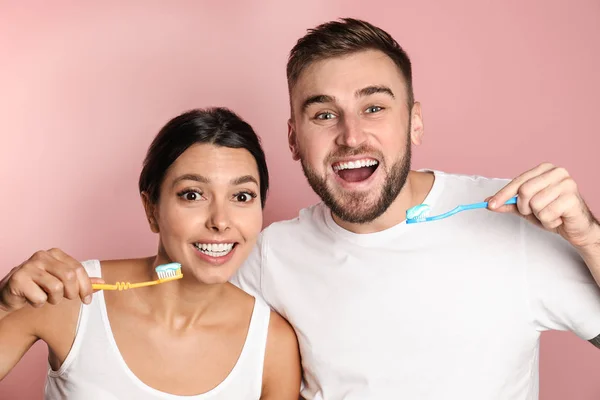 Νέος ζευγάρι με οδοντόβουρτσες και επικόλλησης στο χρώμα φόντου. Φροντίδα των δοντιών — Φωτογραφία Αρχείου