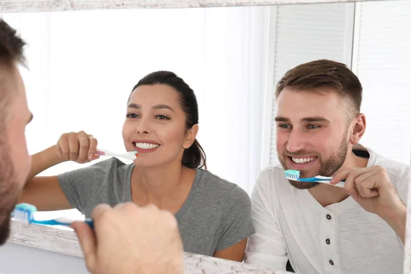 Junges Paar putzt Zähne gegen Spiegel im Badezimmer — Stockfoto