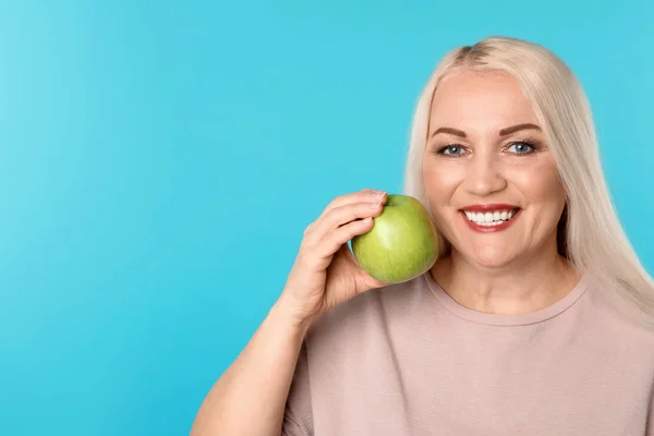 Улыбающаяся женщина с идеальными зубами и зеленым яблоком на цветном фоне. Пространство для текста — стоковое фото