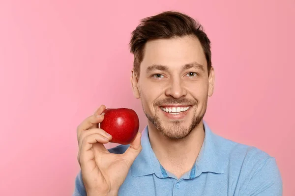 Smiling man with perfect teeth and red apple on color background — Stock Photo, Image