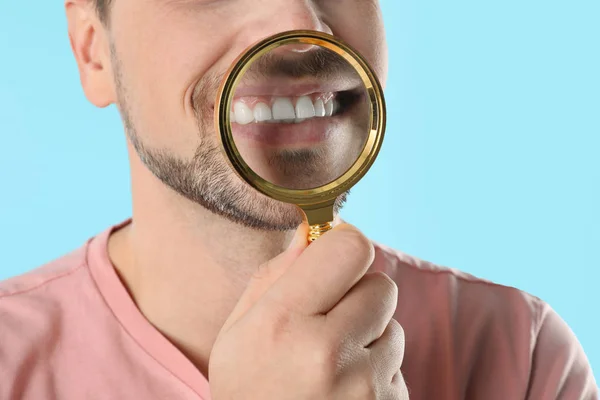 Homem sorridente com dentes perfeitos e lupa sobre fundo de cor, close-up — Fotografia de Stock