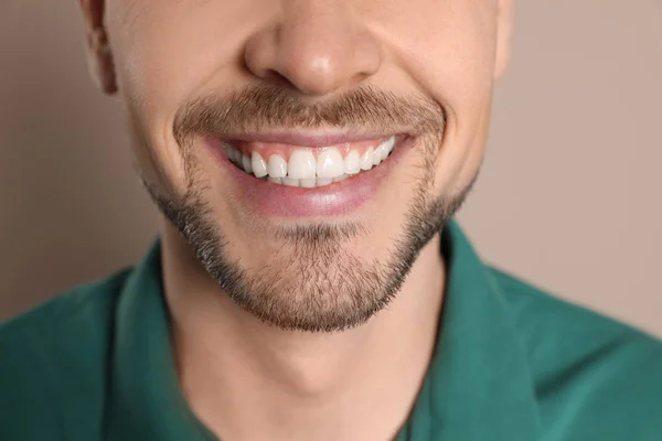 Uomo sorridente con denti perfetti su sfondo di colore, primo piano — Foto Stock