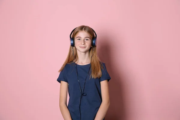 Chica adolescente escuchando música con auriculares en el fondo de color —  Fotos de Stock