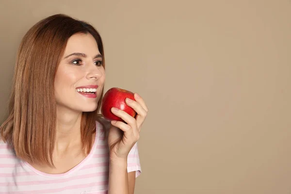 Mujer sonriente con dientes perfectos y manzana roja sobre fondo de color. Espacio para texto — Foto de Stock